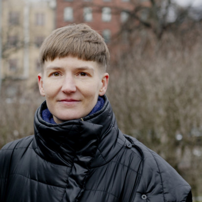 Pilvi Takala hymyilee vasten talvista puistomaisemaa.