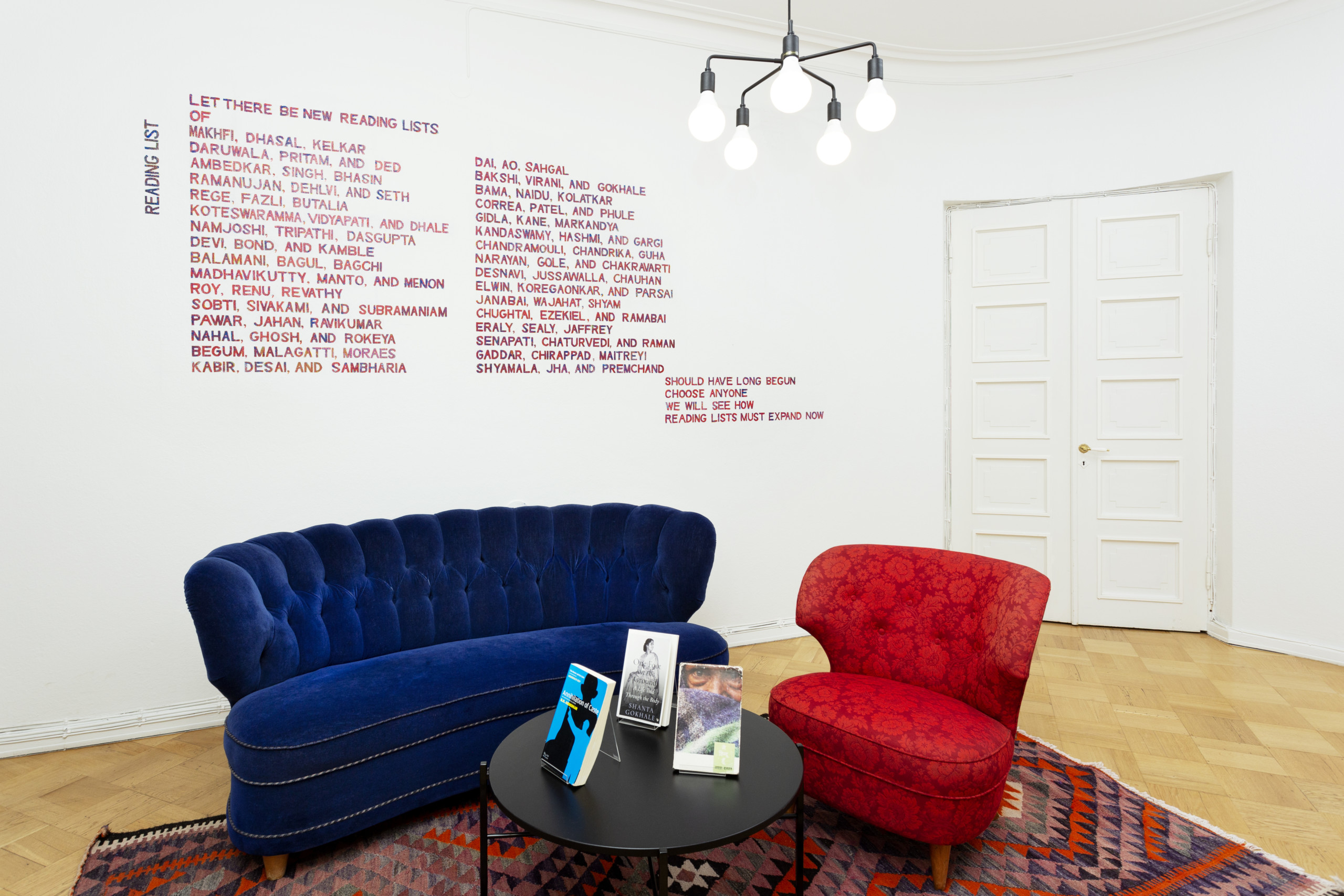 A sofa and an armchair in small room or foyer. Text on the wall.