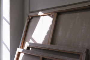 kangas kehykseen pingoitettuna taiteilijan tyohuoneella. Auringonvalo tulee ikkunasta.