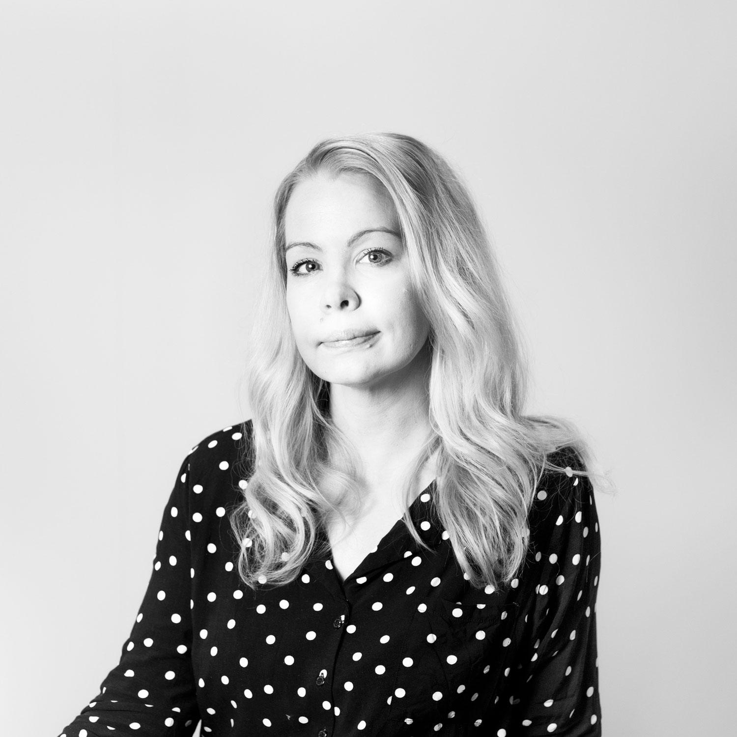 Portrait of a blond white woman wearing a black and white polka dot blouse.