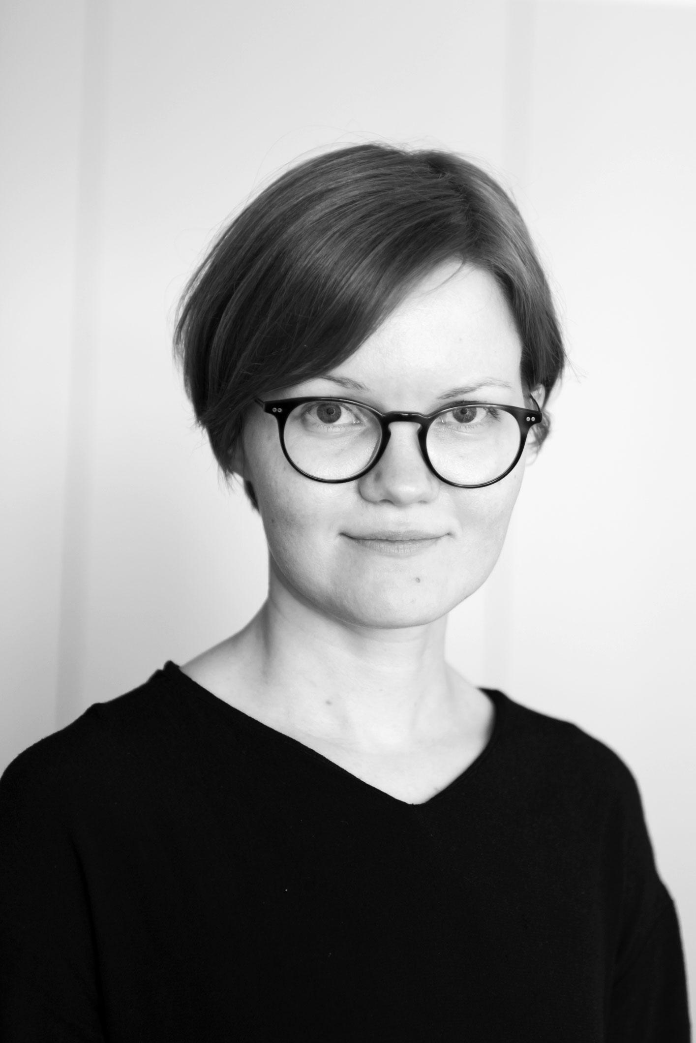 A black and white portrait of a white woman wearing a black shirt looking straight into the camera