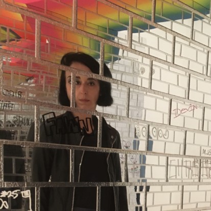 An image of tile-shaped mirrors that reflect Xenia Kalpatsoglou looking directly at the camera.