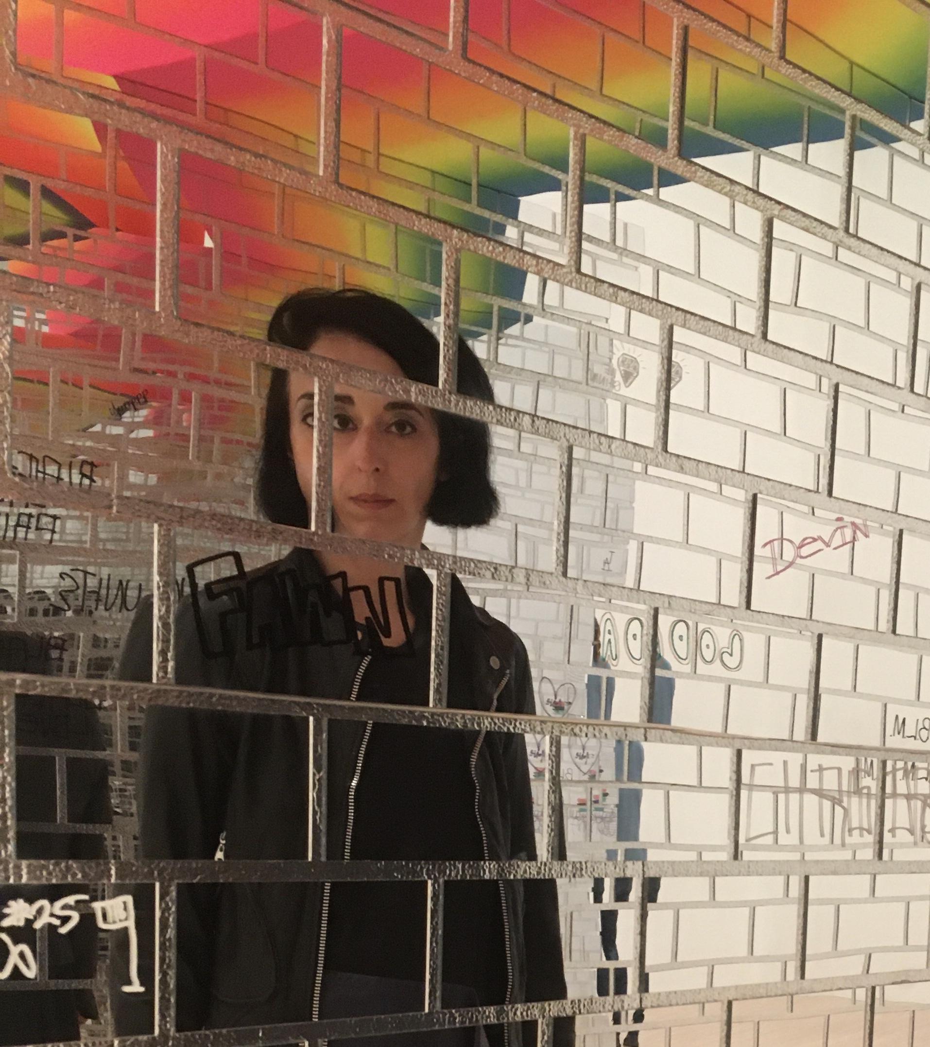 An image of tile-shaped mirrors that reflect Xenia Kalpatsoglou looking directly at the camera.