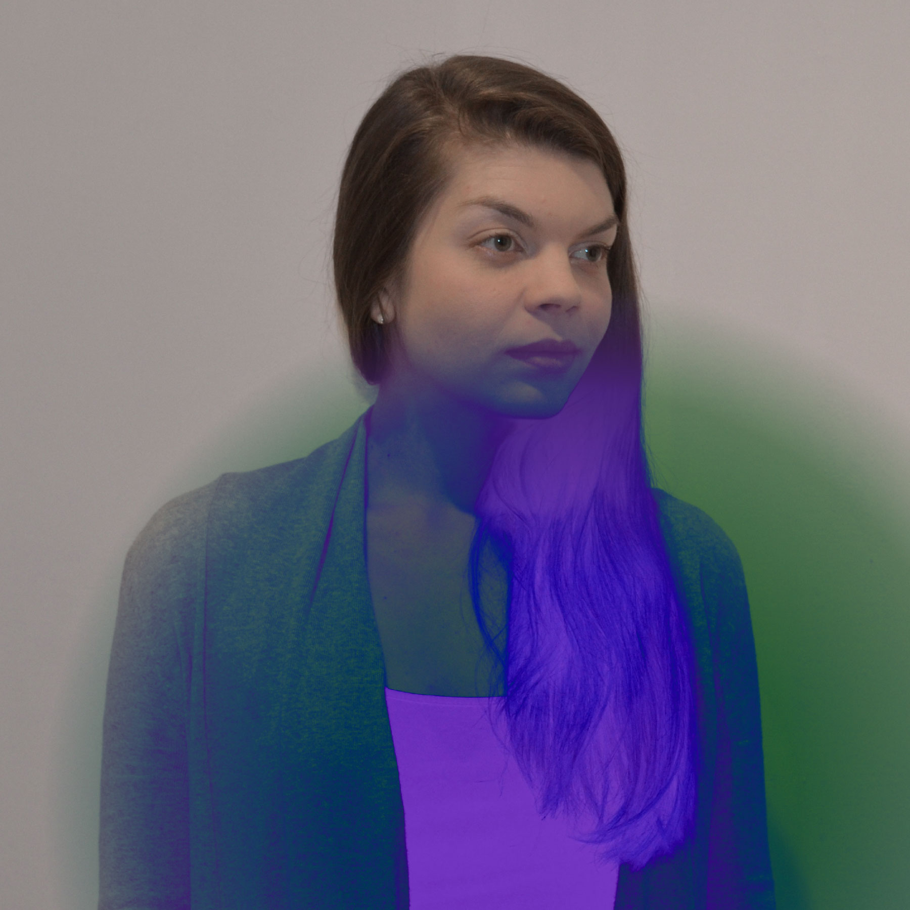 A light-skinned woman with long dark hair looks away from the camera in a diagonal direction. The lower right quadrant of the image looks digitally manipulated to give it a bright blue and purple exposure.