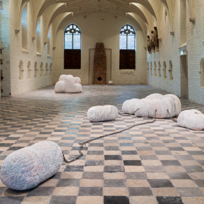 A sculpture installation consisting of four sculptures connected to each other with chains. The marble sculptures have soft shapes.