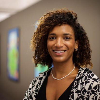A portrait of a person with brown skin and curly dark brown hair.