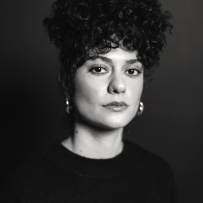A black and white portrait of a person with light skin and curly dark hair in an updo.