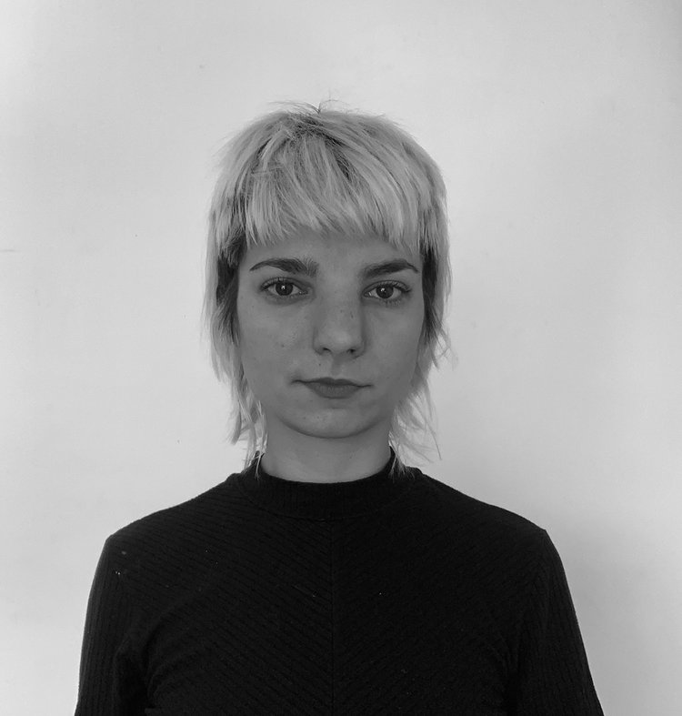 A black and white photo of a light skinned person with short, light hair wearing a dark shirt