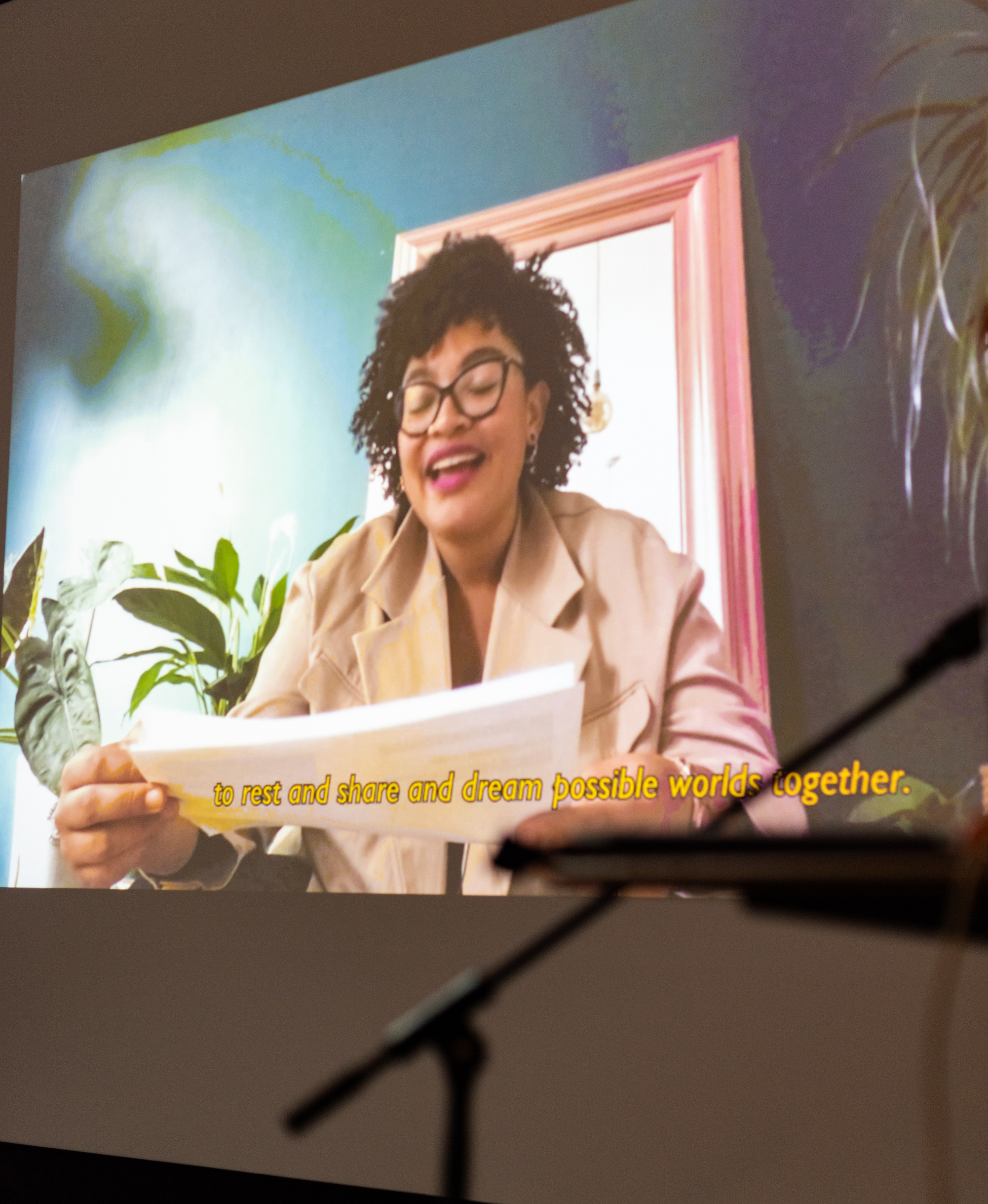 Ama Josephine Budge presenting her writing 'Pleasurable Ecologies – Formations of Care: The Impossibilities of Invitation' in a projector screen video broadcast.