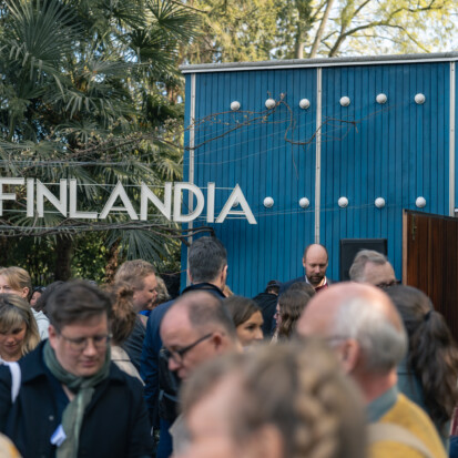 Still shot of the opening day of the 59th Venice Biennale. People are talking ad standing in front of the blue Aalto Pavilion.